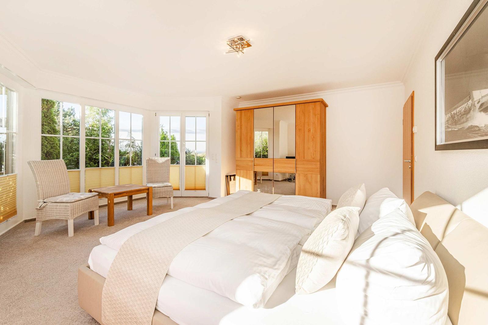 Schlafzimmer mit Doppelbett, Schrank und Fensterblick auf Garten
