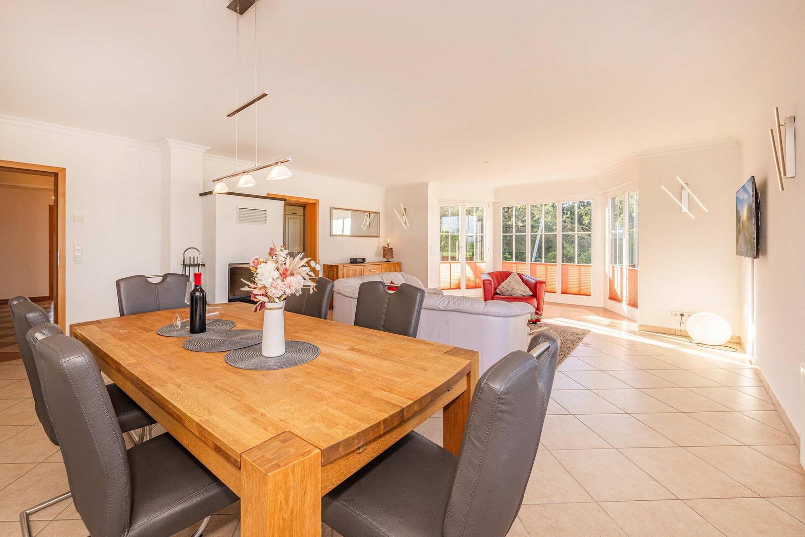 Esszimmer mit Holztisch und Stühlen, Wohnzimmer mit Sofa und Fenster