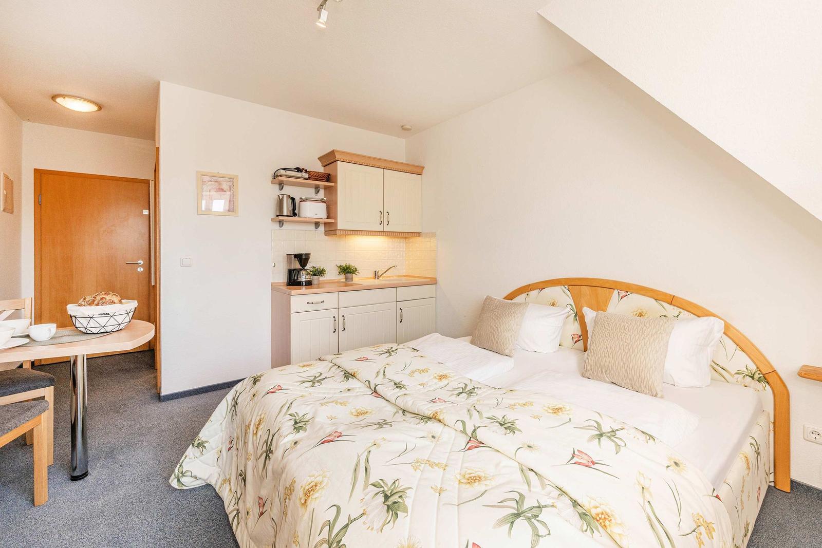 Schlafzimmer mit Doppelbett, kleiner Küchenzeile und Essbereich.