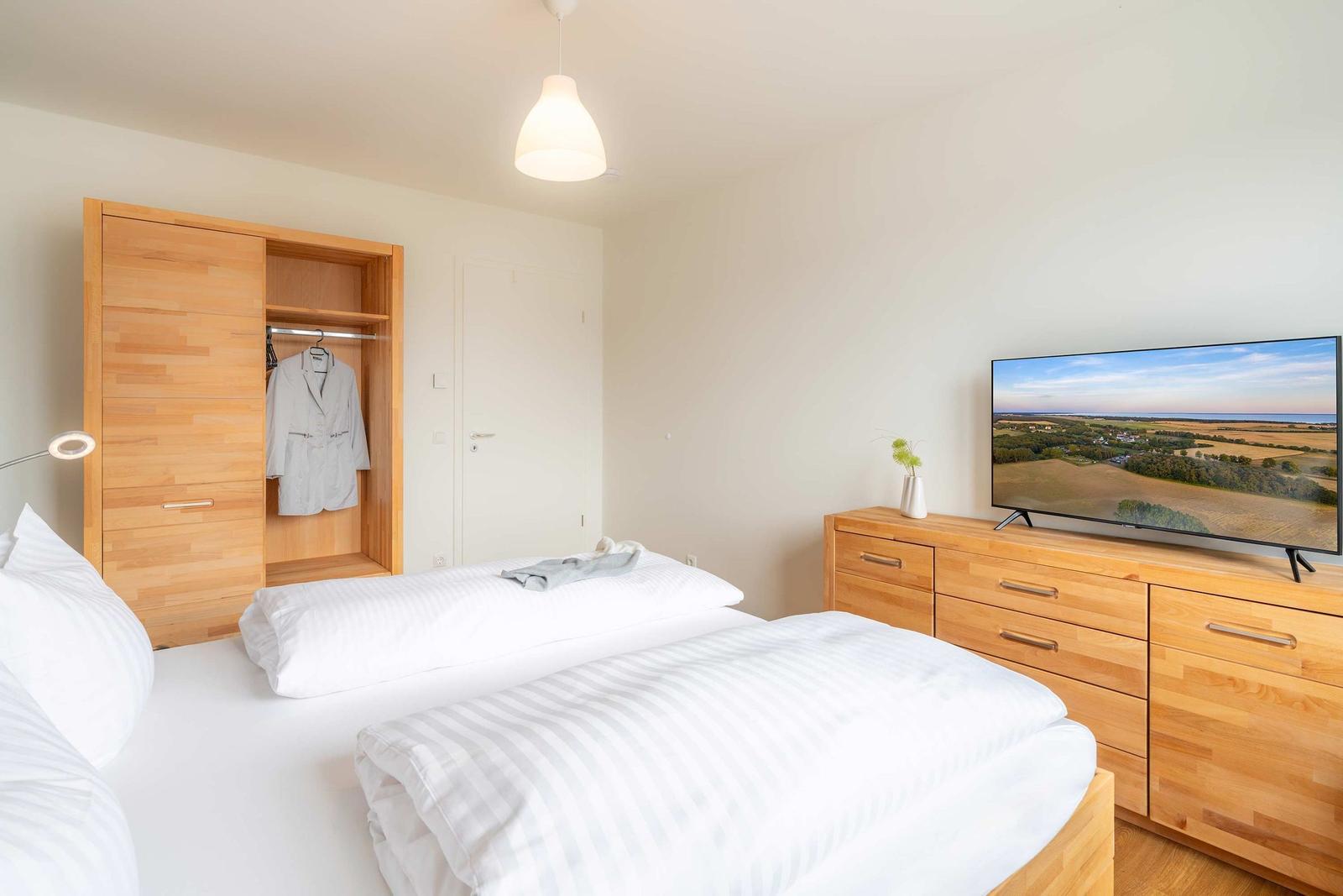 Schlafzimmer mit Bett, Kleiderschrank und Fernseher auf Holzschrank.