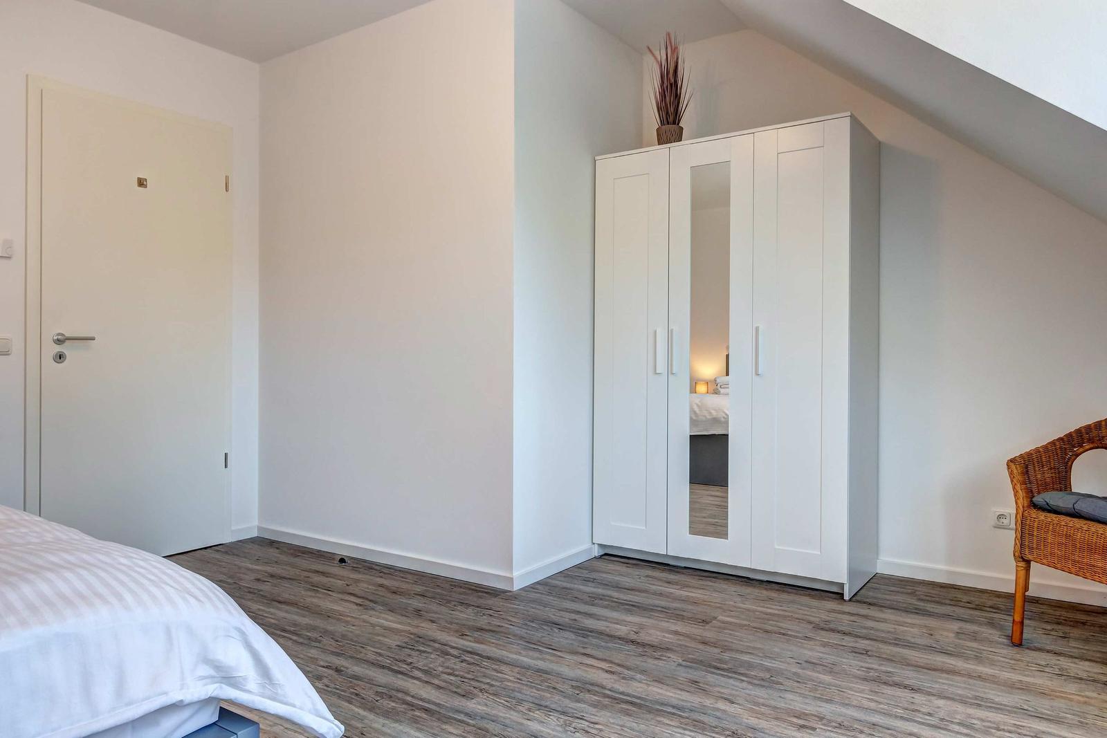 Schlafzimmer mit weißem Schrank, Bett und Stuhl