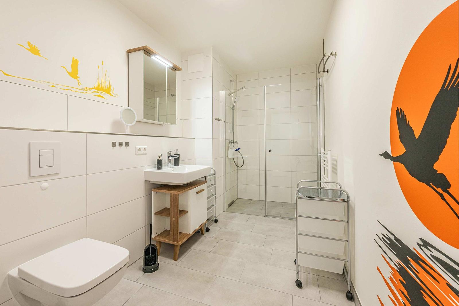 Bathroom with shower, sink, and toilet. Wall decor with bird motifs.