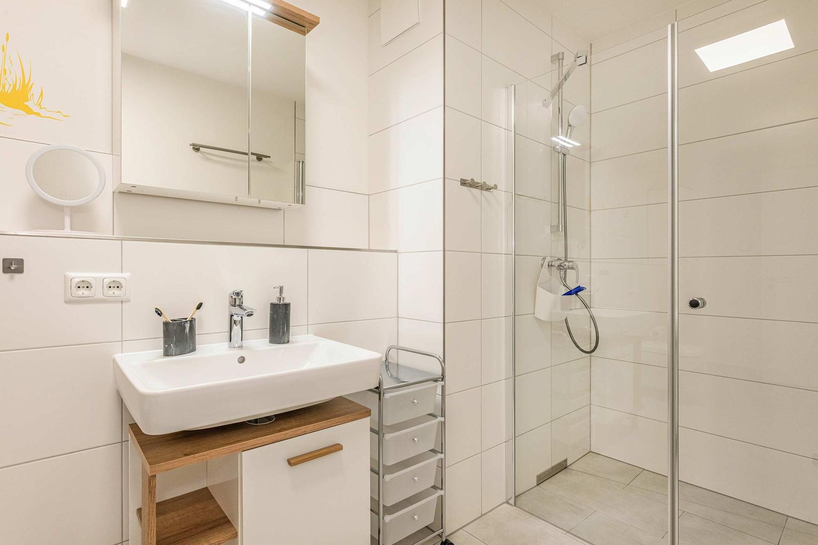 Bathroom with shower, sink, and mirror cabinet.
