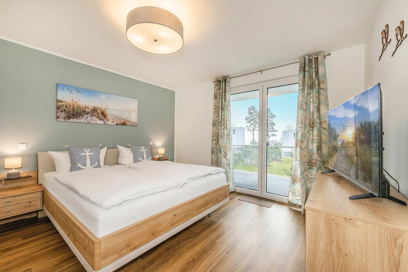 Bedroom with double bed, TV, and balcony view.