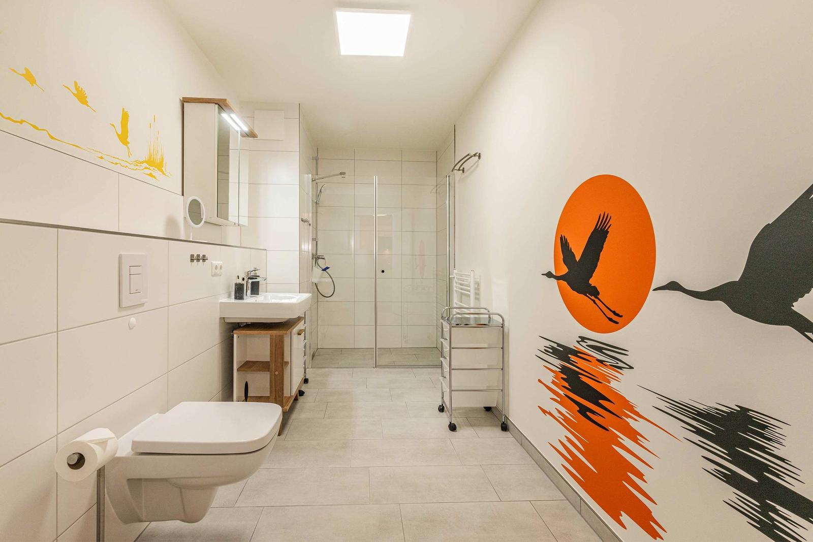 Bathroom with shower, sink, and toilet. Wall decor with bird motifs.