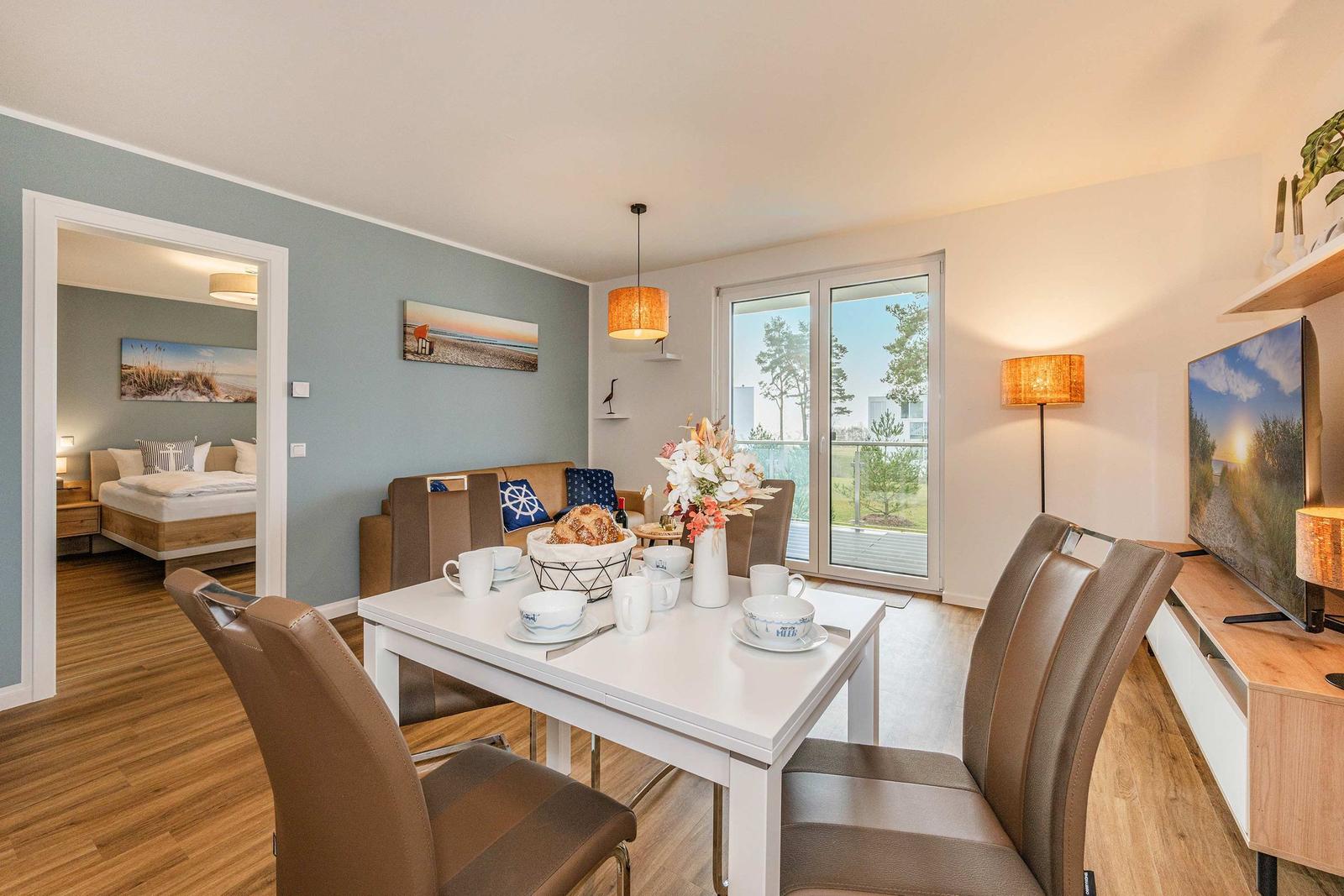 Dining room with table, chairs, and view of balcony. Living room and bedroom are visible.