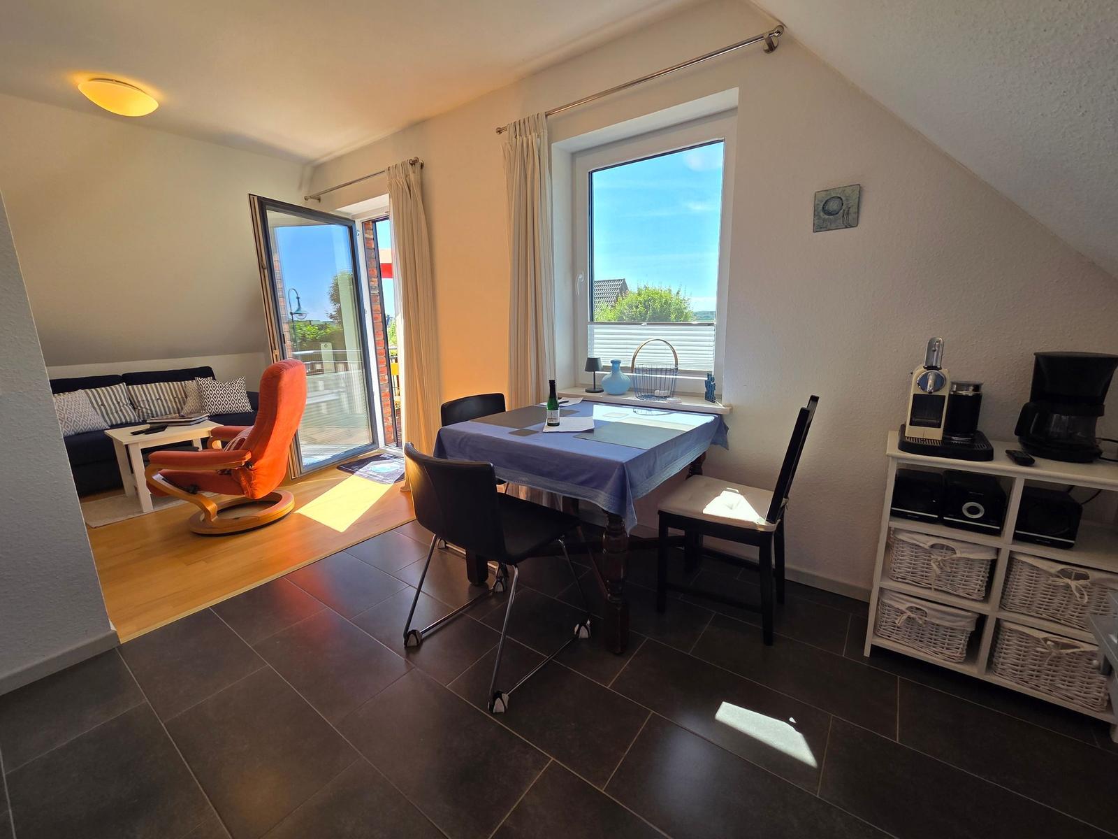 Esszimmer mit Tisch, Stühlen und Fenster. Wohnbereich mit Sofa und Terrassentür.