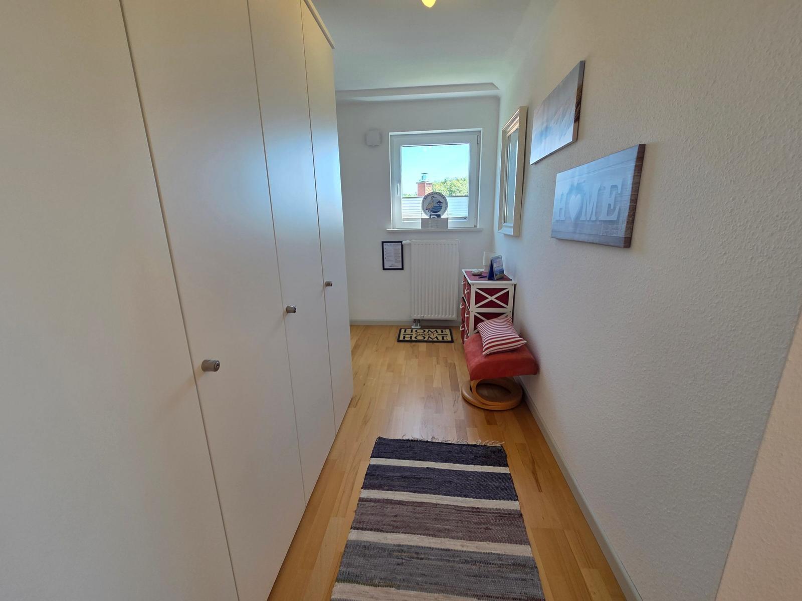 Flur mit Kleiderschrank, Teppich und Sitzbank an der Wand.