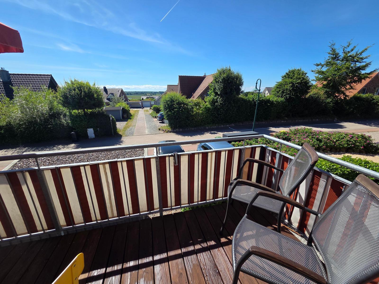 Terrasse mit zwei Stühlen und Blick auf Straße und Häuser.