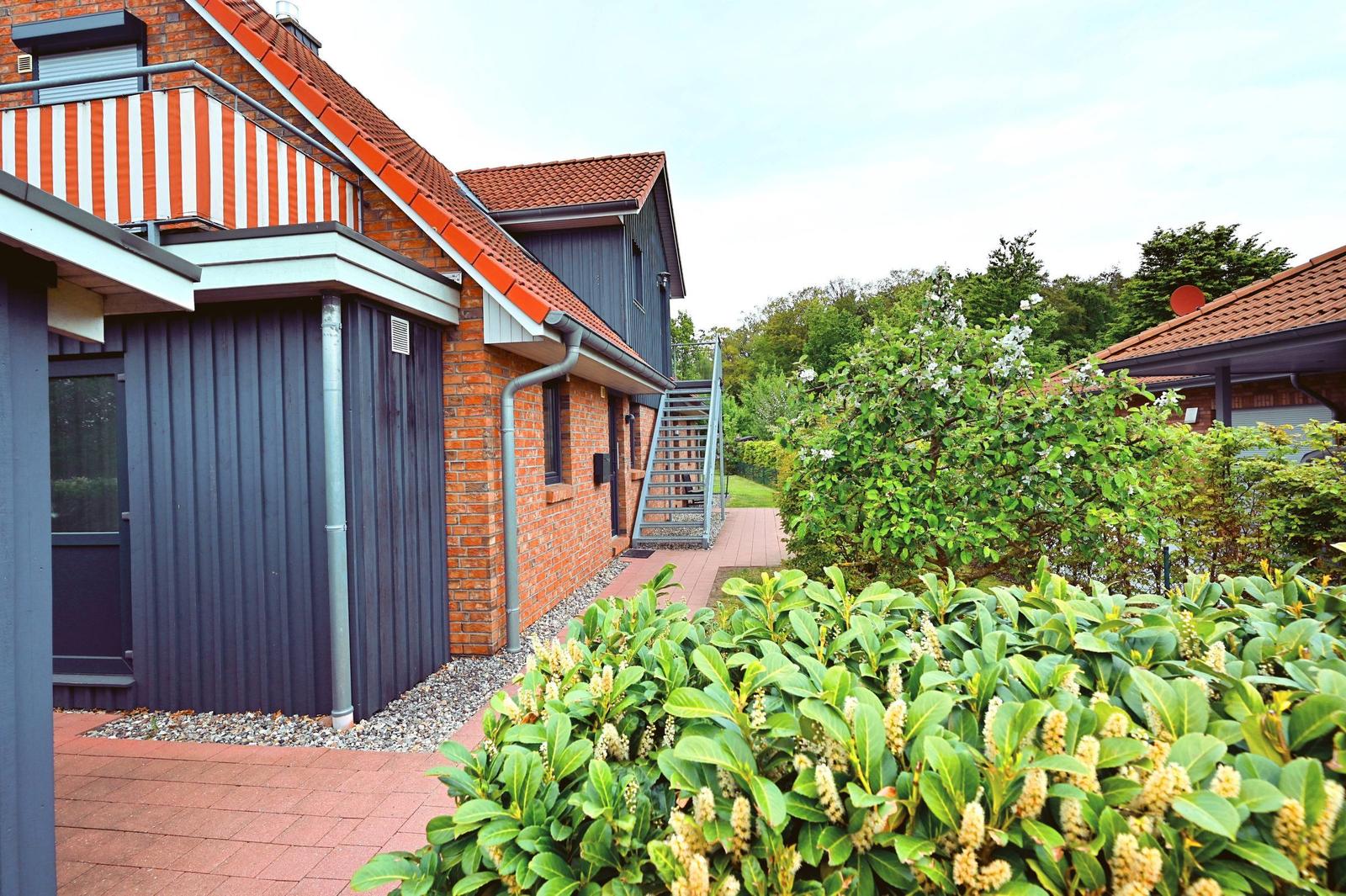 Haus mit Terrasse, grüner Garten und rotem Ziegeldach.