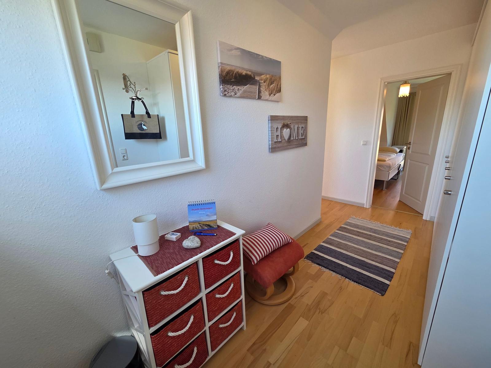 Flur mit Schrank, Spiegel und Bildern. Tür führt ins Schlafzimmer.
