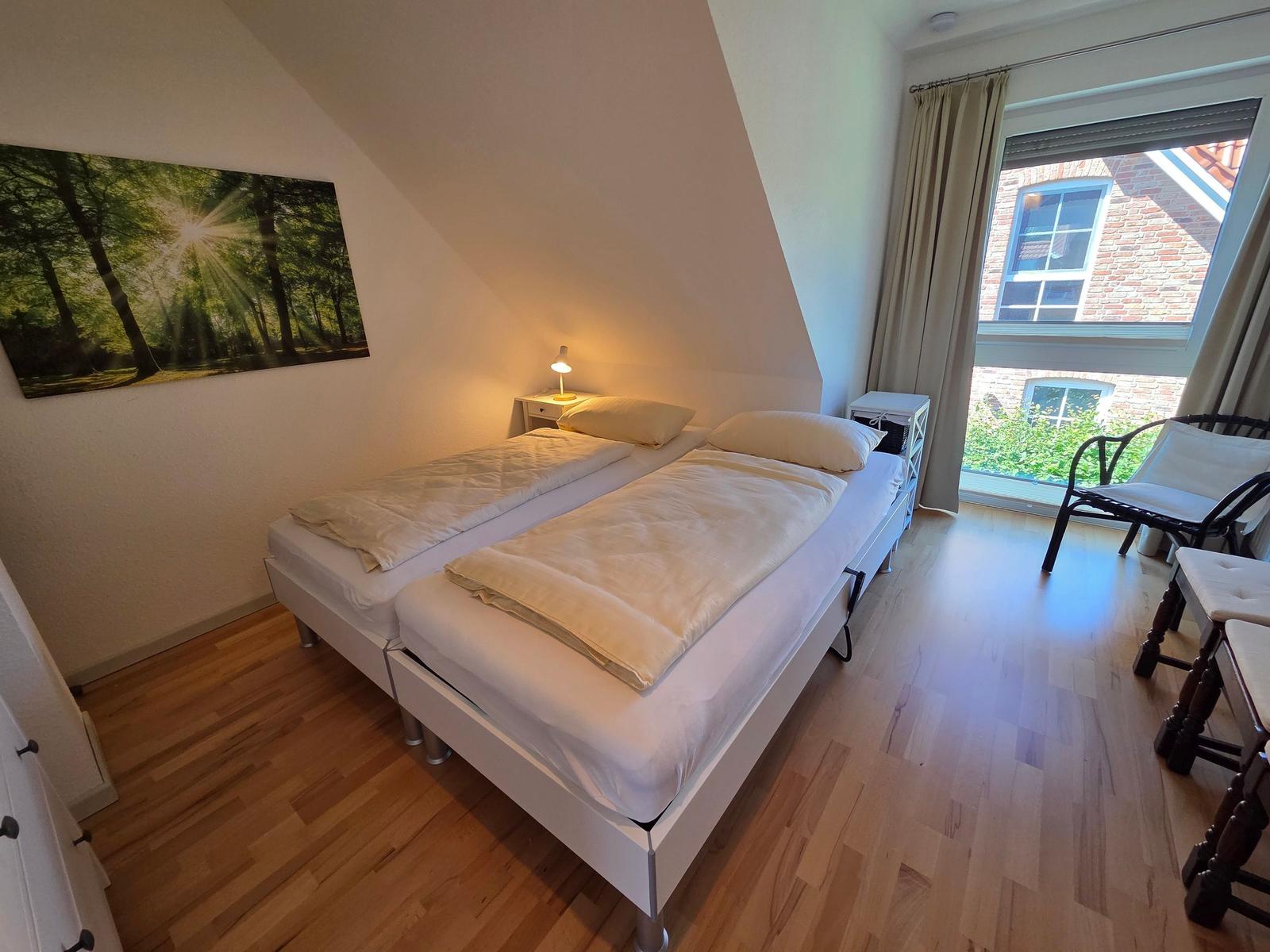Zimmer mit Doppelbett, Holzboden und Fensterblick auf Haus