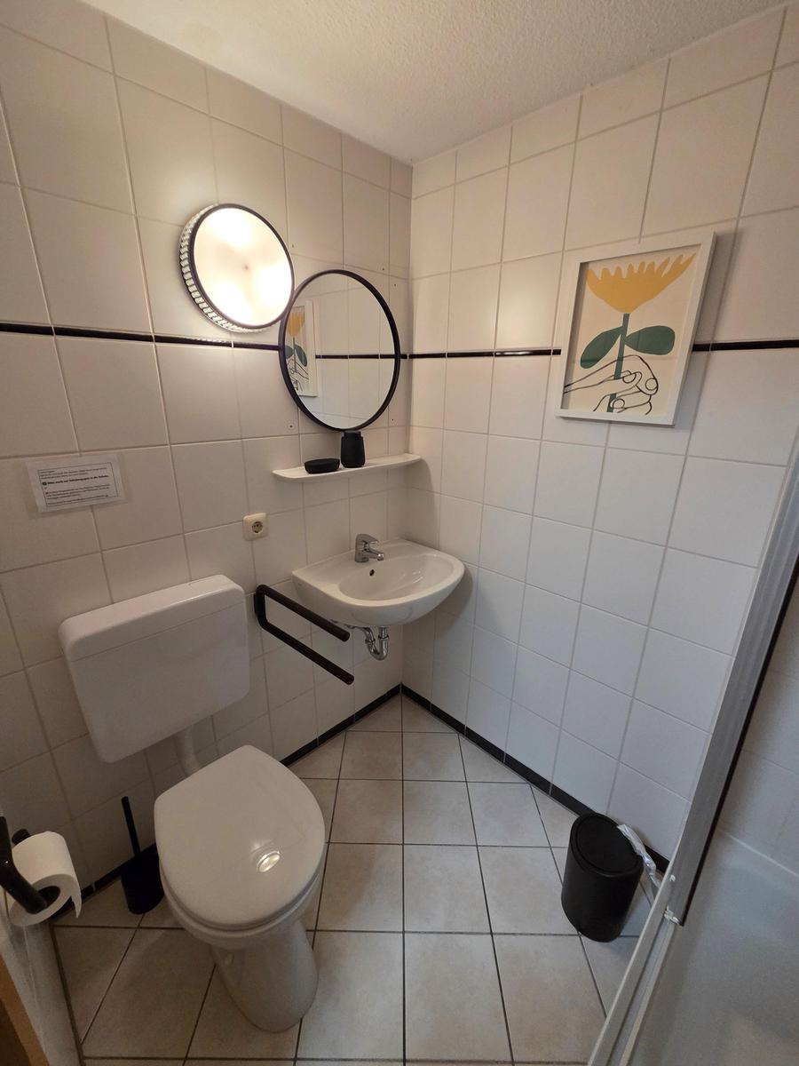 Badezimmer mit Toilette, Waschbecken und Spiegel an der Wand.