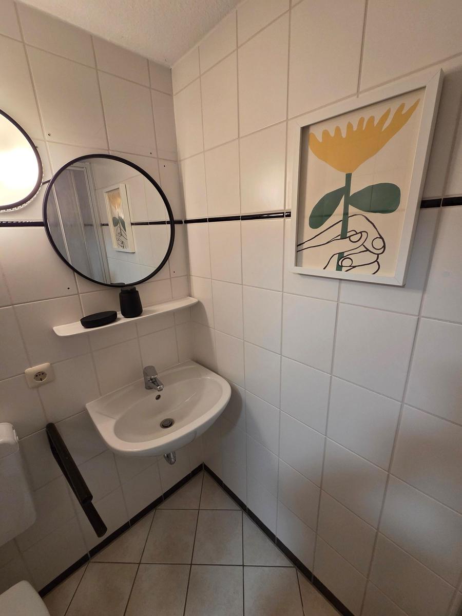 Badezimmer mit Waschbecken, Spiegel und Wandbild.
