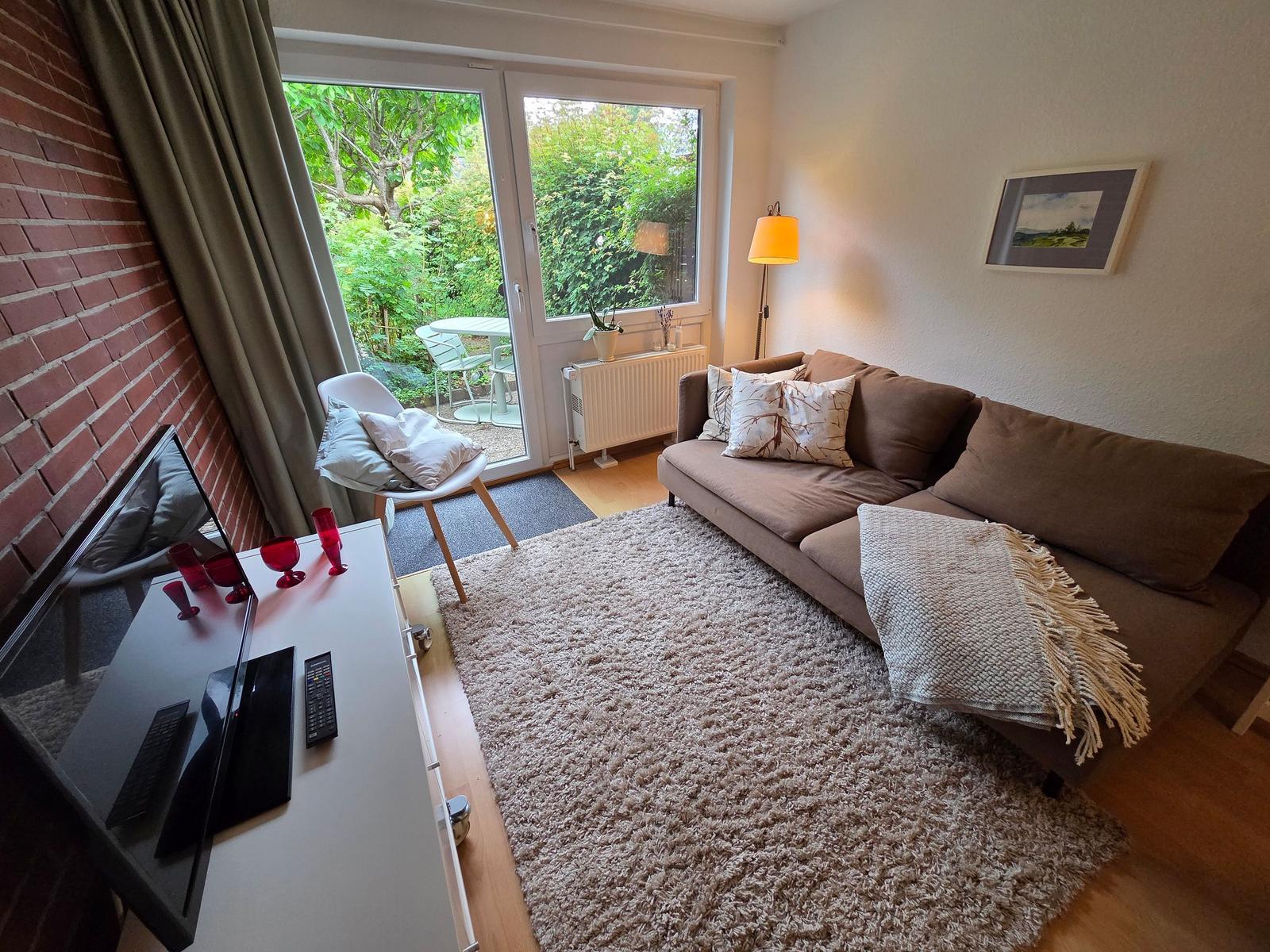 Wohnzimmer mit Sofa, Teppich und Blick auf den Garten.