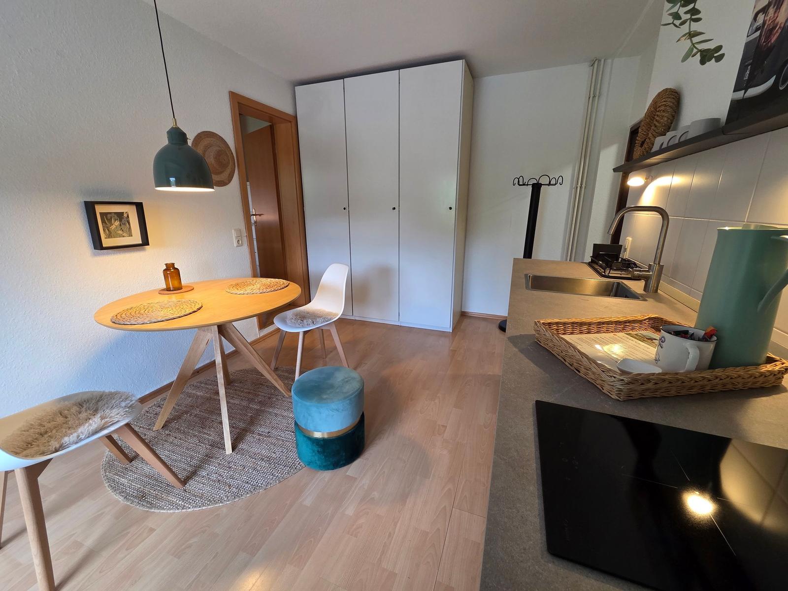 Küche mit Essbereich, weißer Schrank und Holzboden.