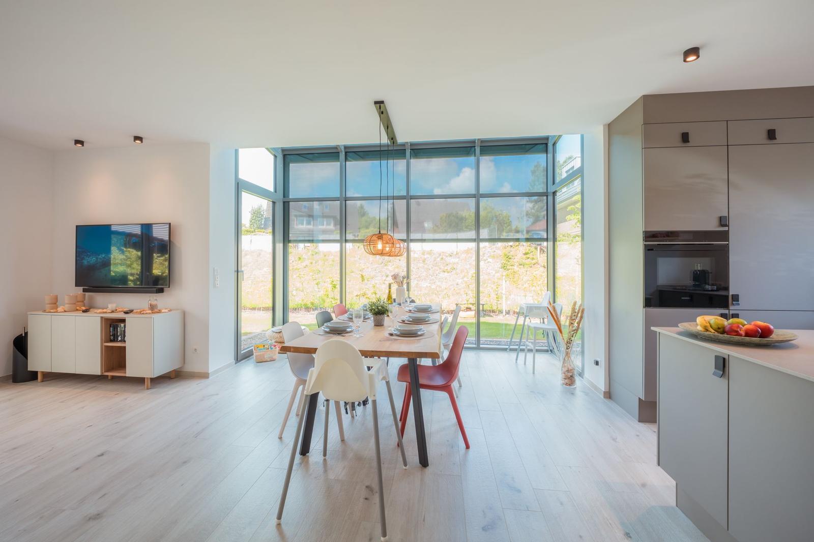 Moderne Küche mit Essbereich und großem Fensterblick auf Garten.