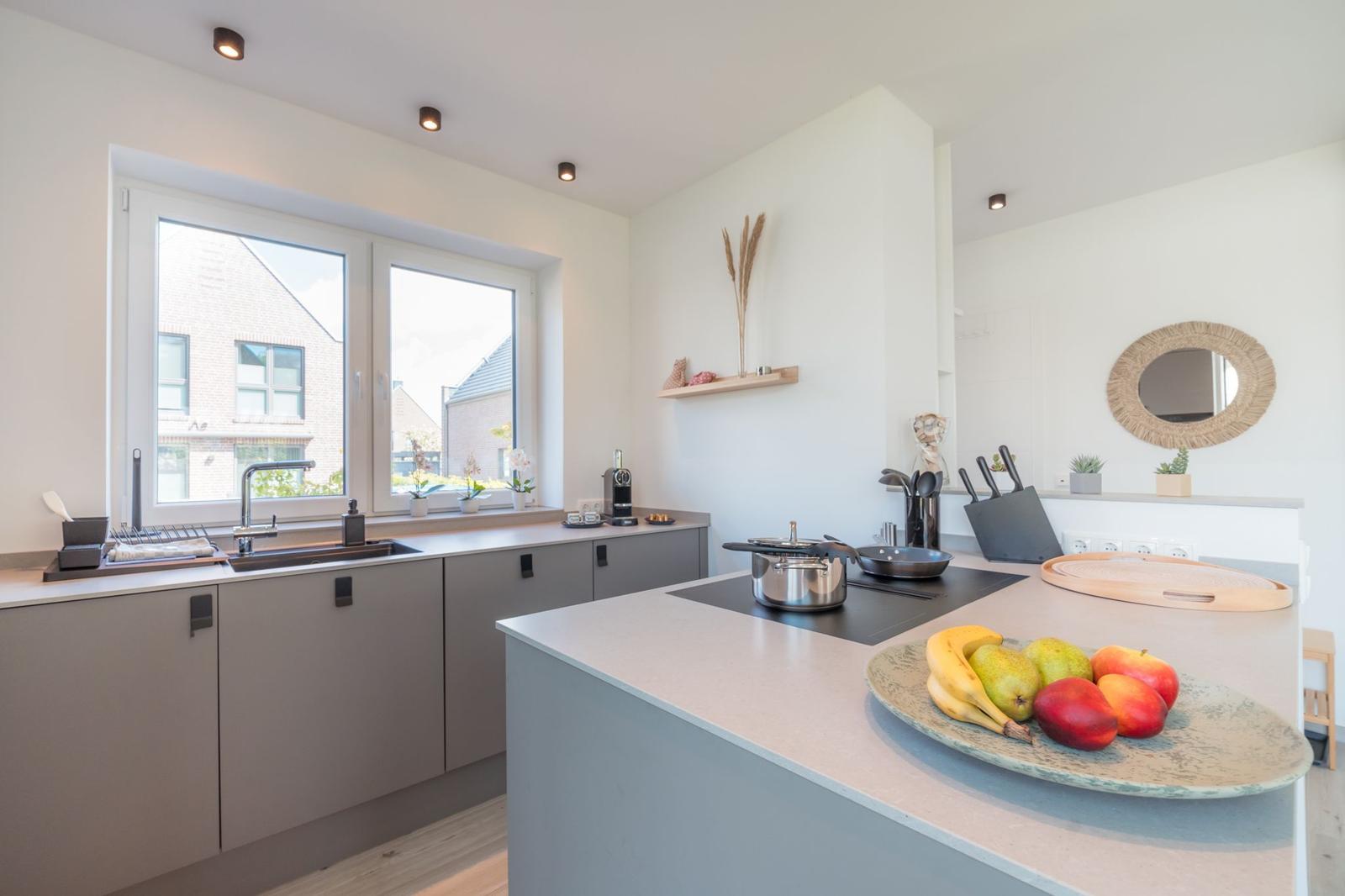 Moderne Küche mit Kücheninsel, Fenster und Obst auf Tisch.