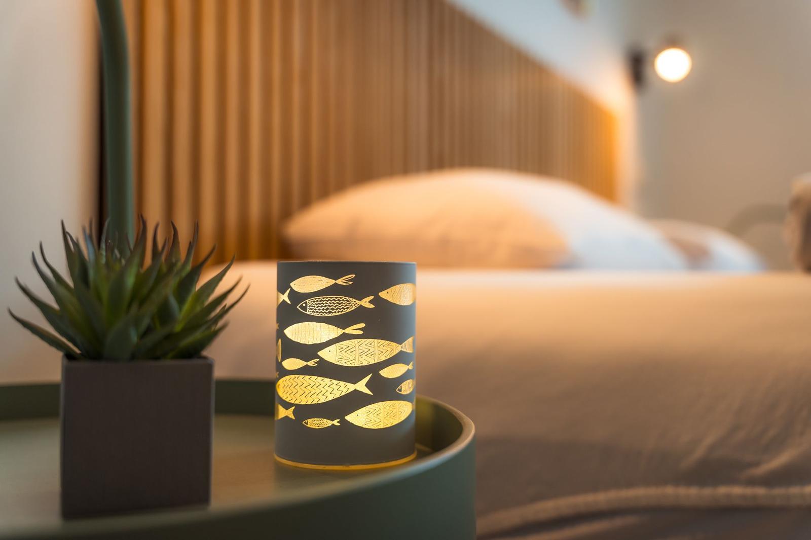 Nachttisch mit Laterne und Pflanze vor Bett