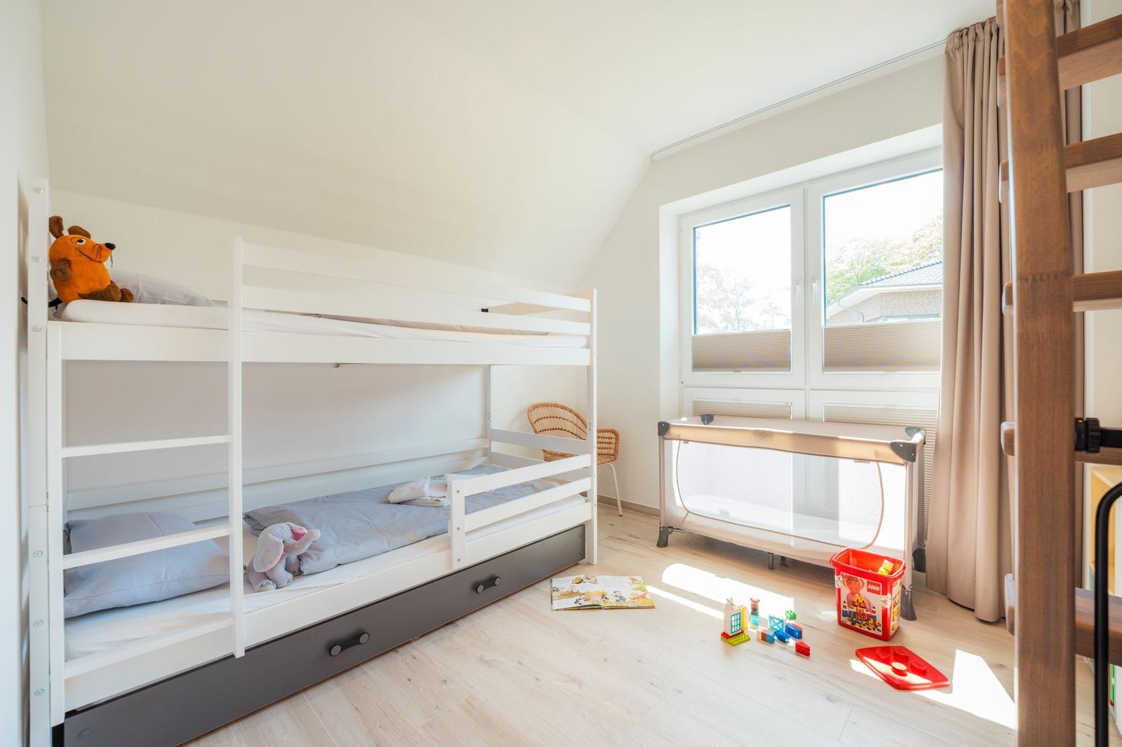 Kinderzimmer mit Doppelstockbett, Spielzeug und Fenster.