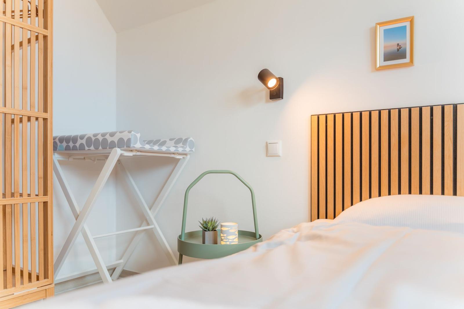 Schlafzimmer mit Bett, Nachttisch und Wäscheständer.