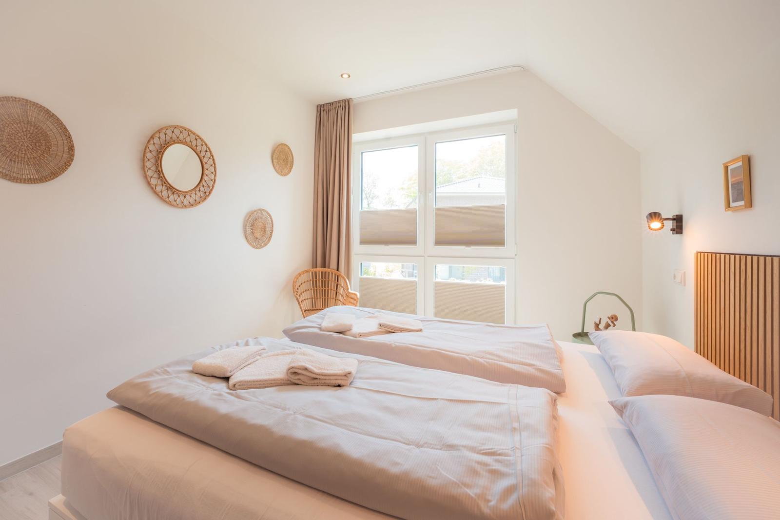 Schlafzimmer mit Doppelbett, Fenster und Wanddekoration.