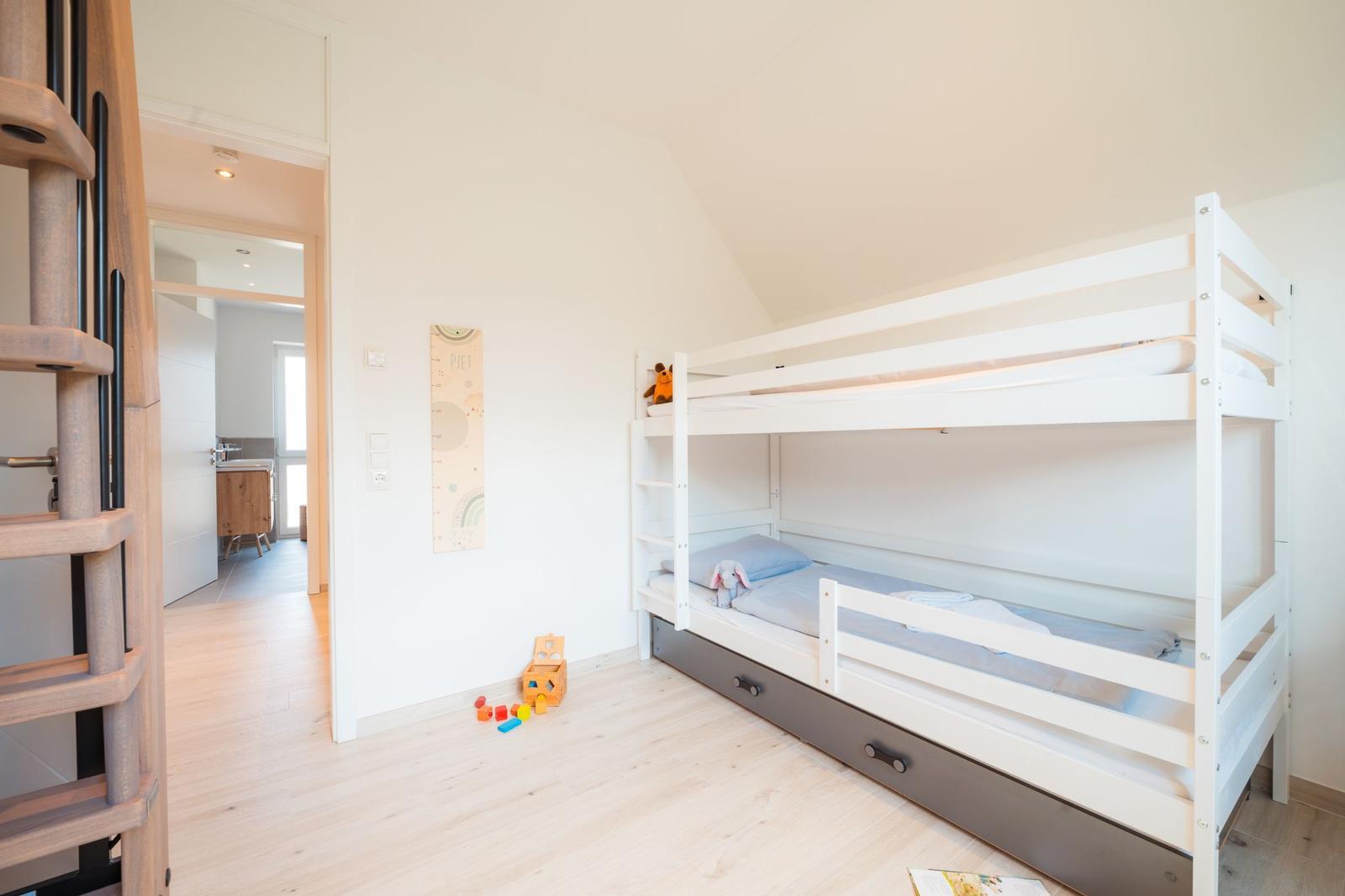 Ein Schlafzimmer mit Doppelstockbett, Spielzeug und einem Wachstumskasten an der Wand.