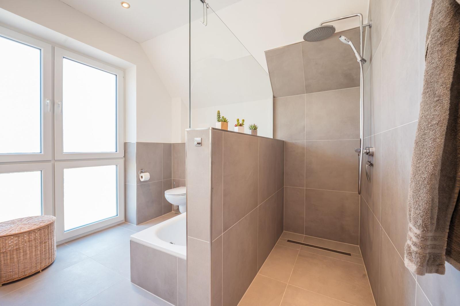 Badezimmer mit Dusche, Badewanne und großem Fenster
