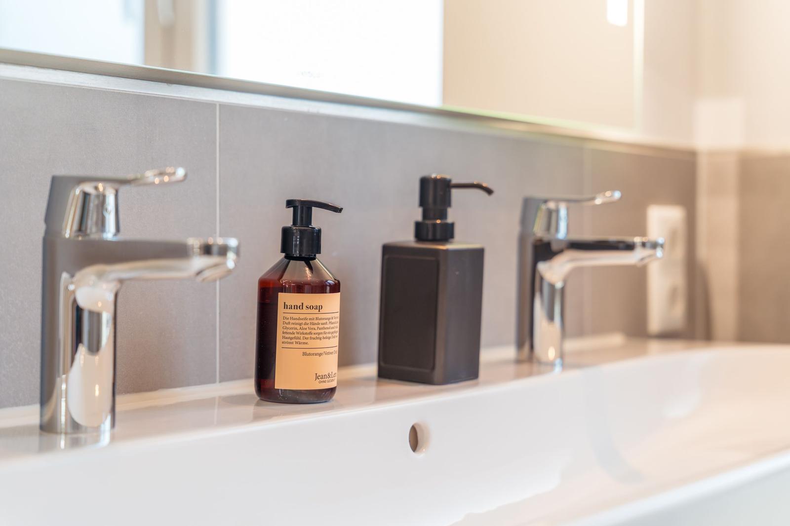 Badewanne mit zwei Wasserhähnen und Seife auf der Ablagefläche.