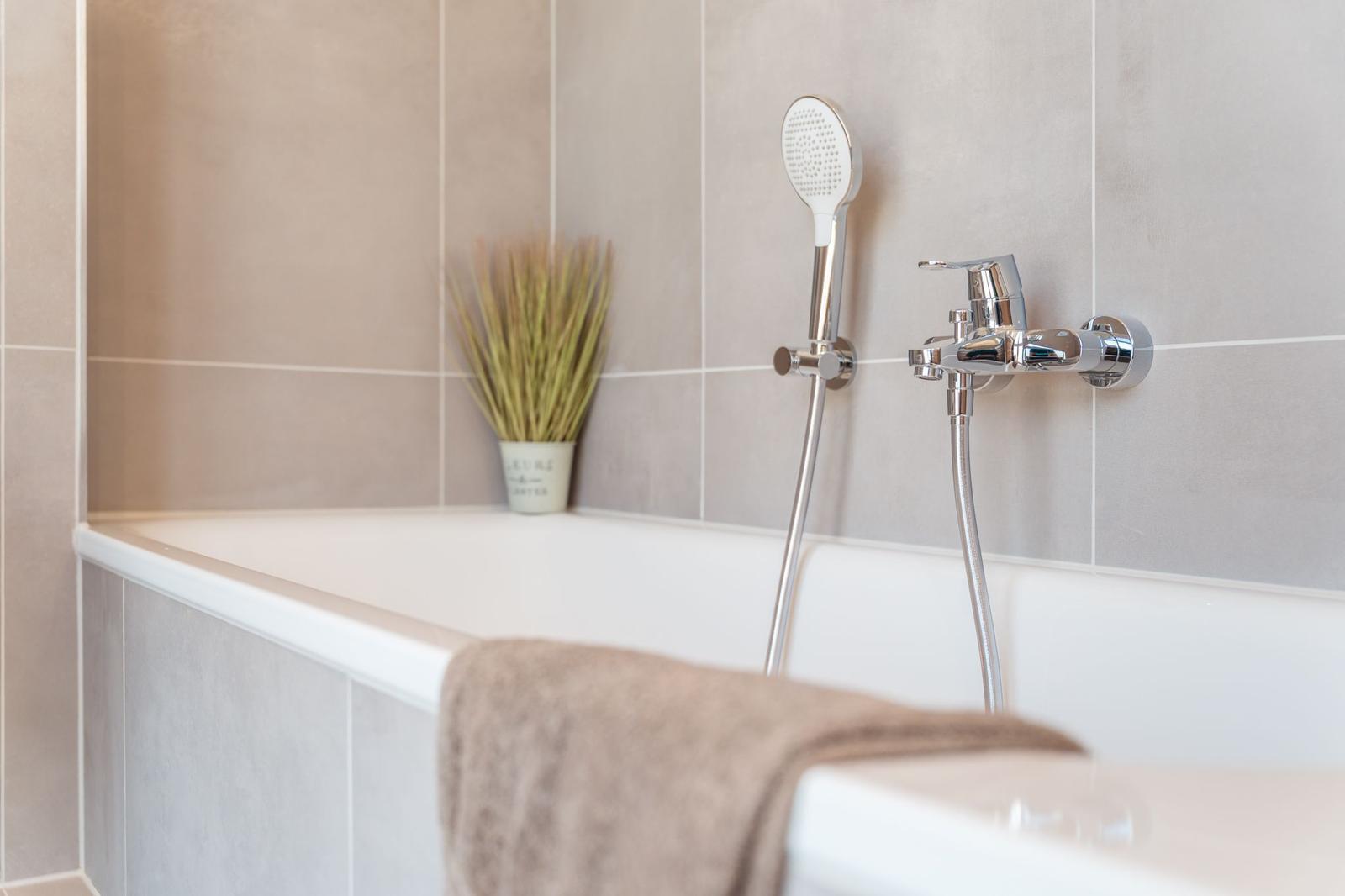 Badewanne mit Duschbrause und Handtuch