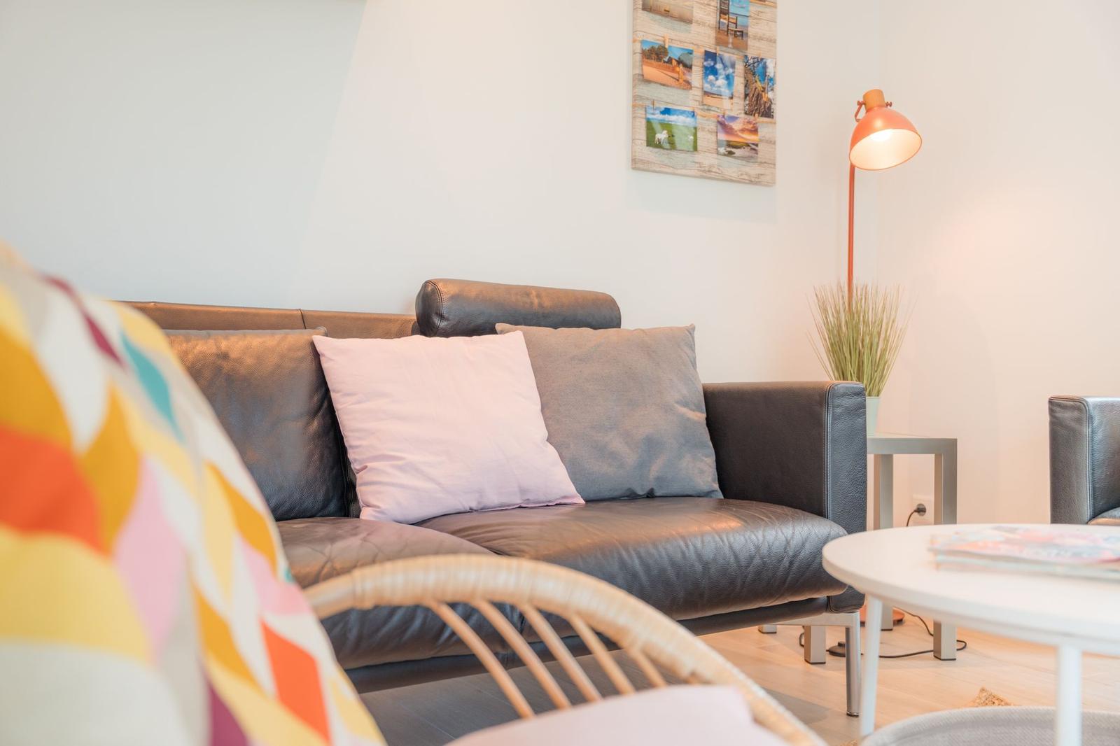 Ein Wohnzimmer mit einem grauen Sofa, Kissen und einer Stehlampe.