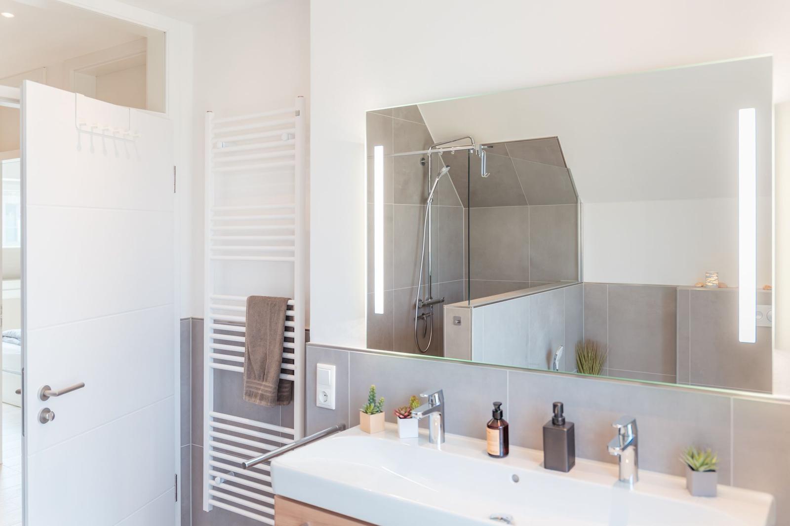 Badezimmer mit Dusche, Spiegel und Waschtisch