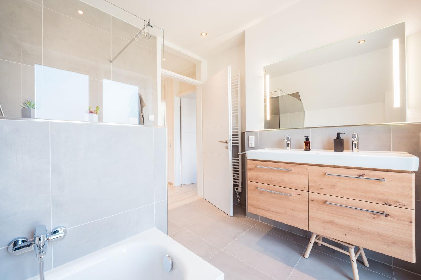 Badezimmer mit Dusche, Badewanne und Holzwaschtisch