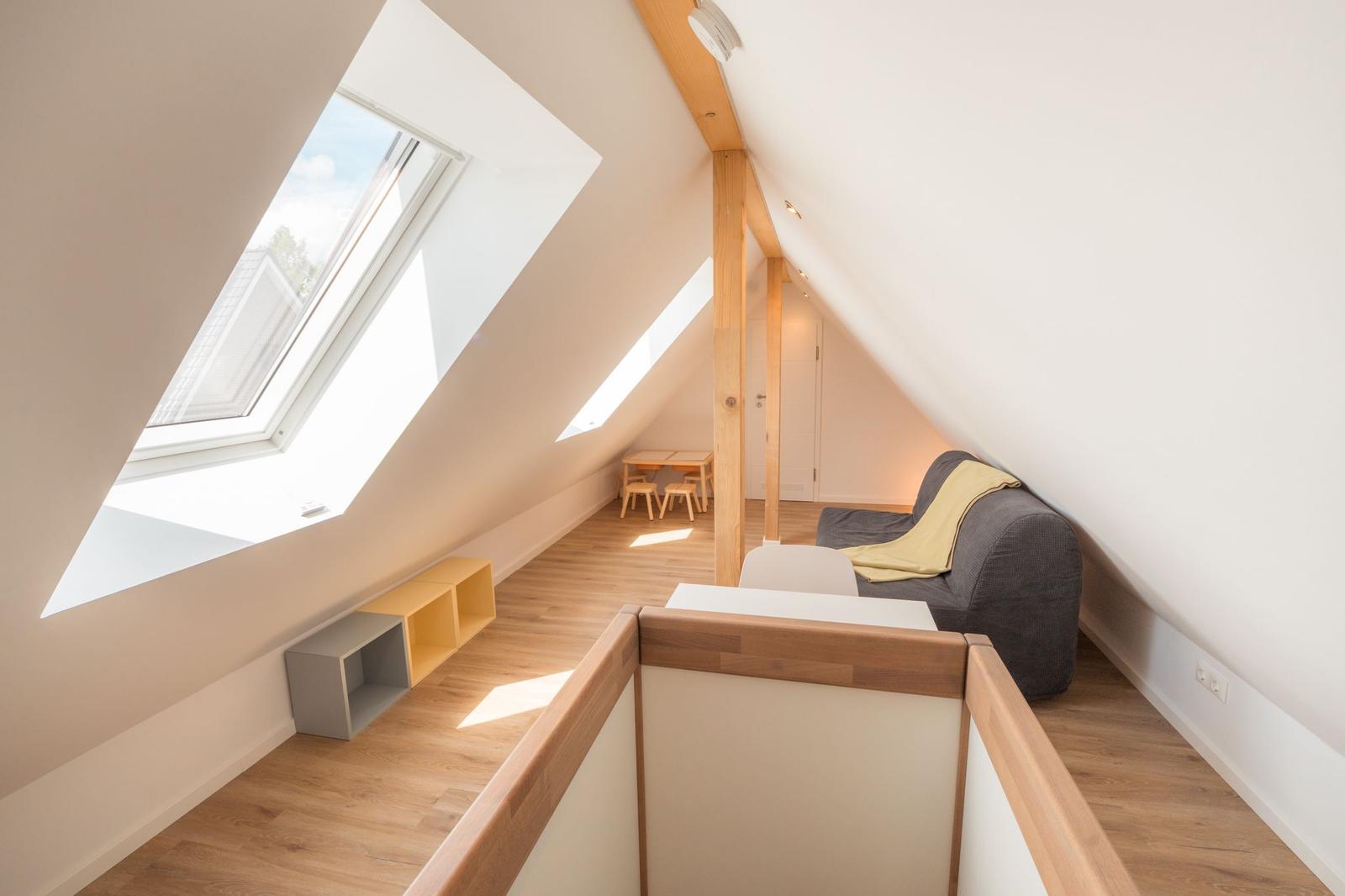 Dachgeschosszimmer mit Dachschrägen, Dachfenster, Sofa und Holzboden.