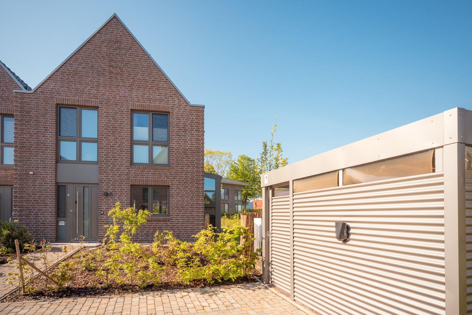 Zwei Stockwerke hohe Backsteinhaus mit Garagenabteil und Gartenbereich.