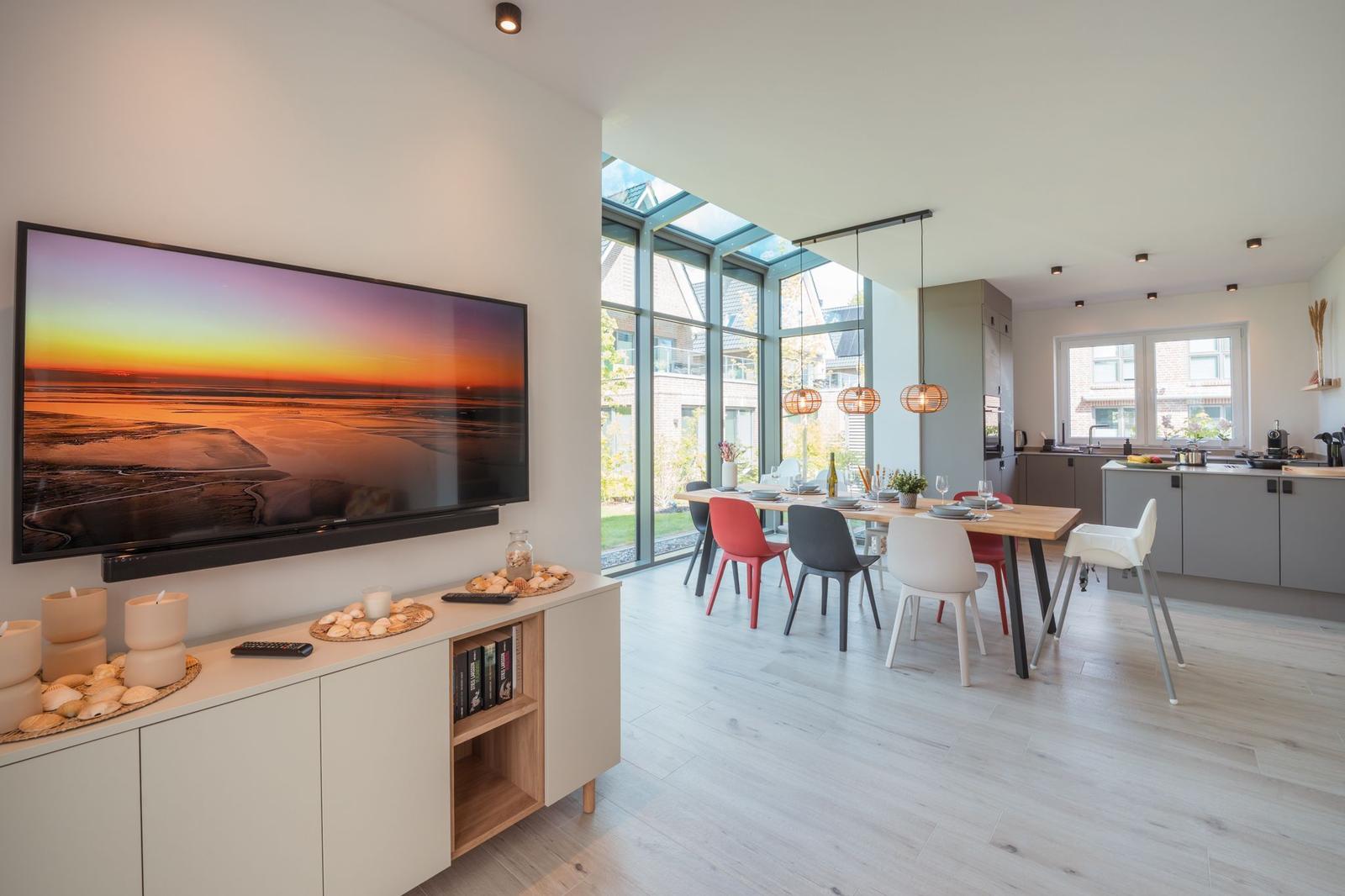 Wohn- und Essbereich mit TV, Esstisch und moderner Küche.