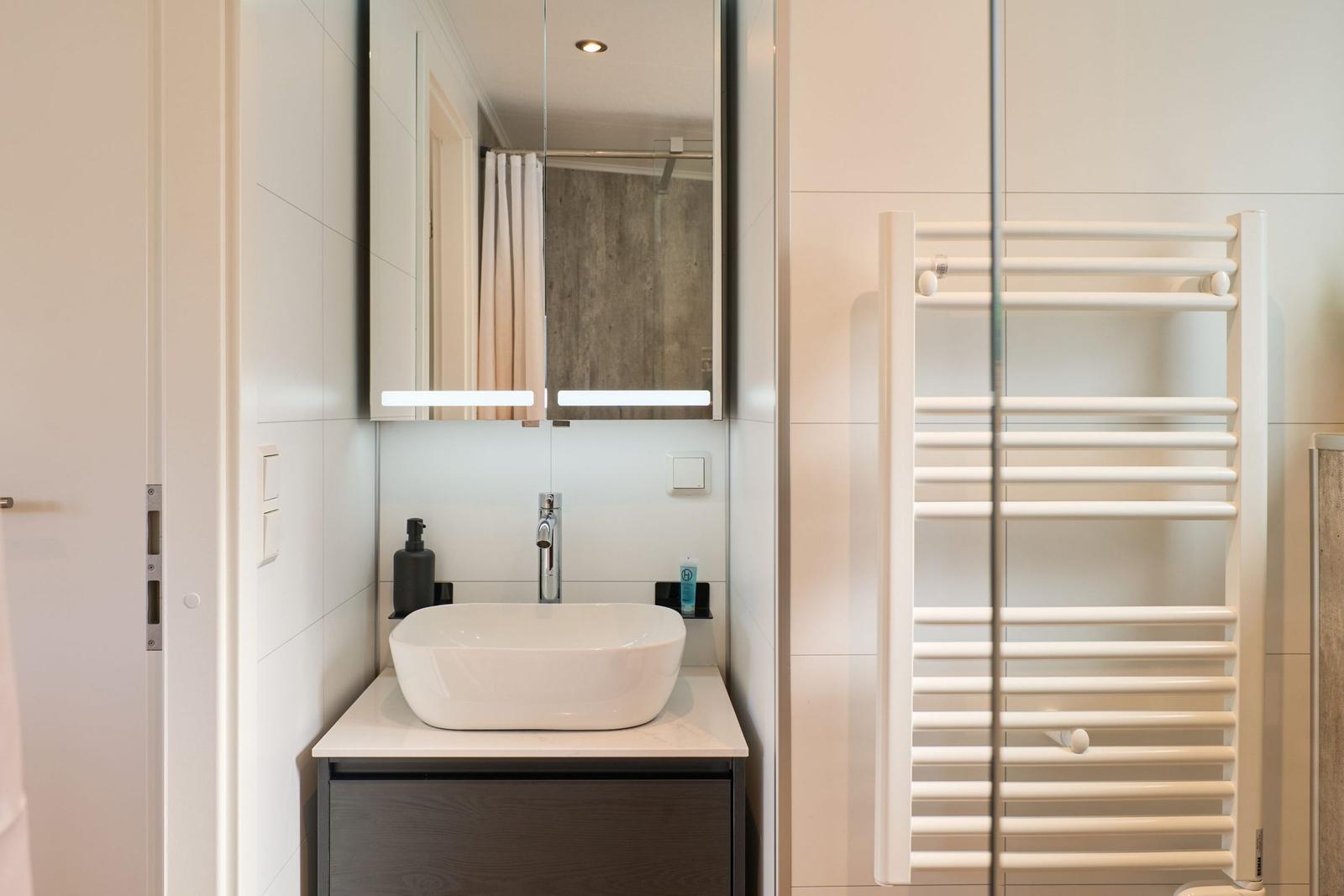 Badezimmer mit Waschbecken, Spiegel und Heizkörper