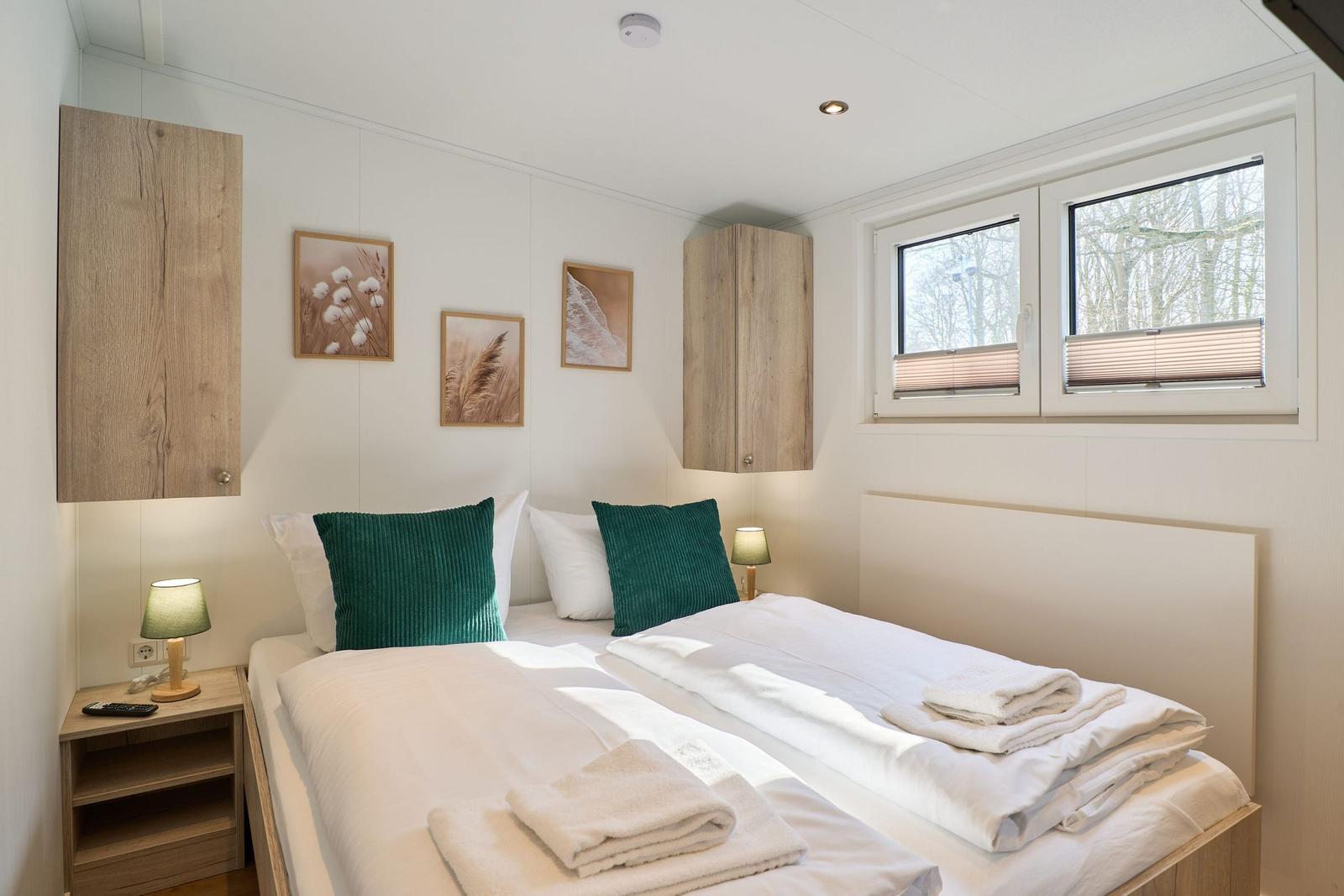 Schlafzimmer mit Doppelbett, Holzmöbeln und Fenster mit Blick auf Bäume.