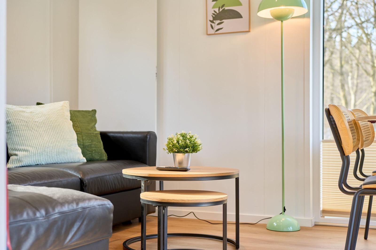 Ein Wohnzimmer mit Sofa, Tisch, Stehlampe und Fenster.