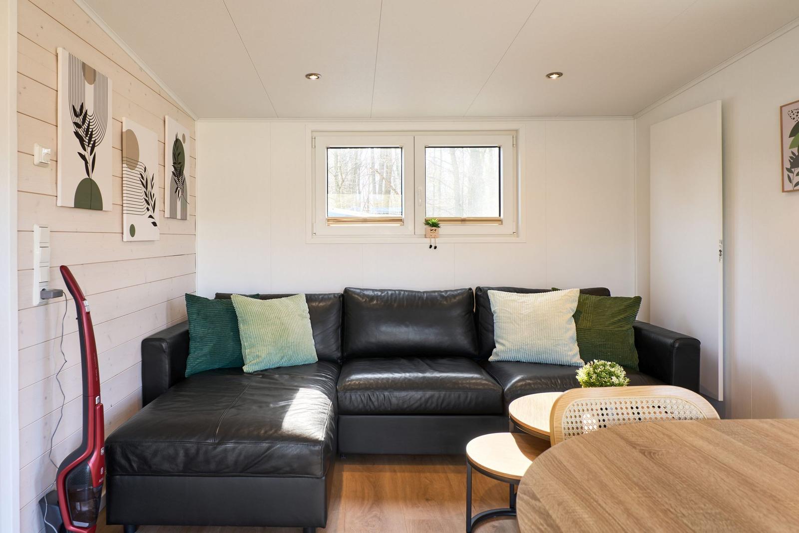 Schwarzes Sofa mit Kissen, Holztisch und Fenster im Wohnbereich.
