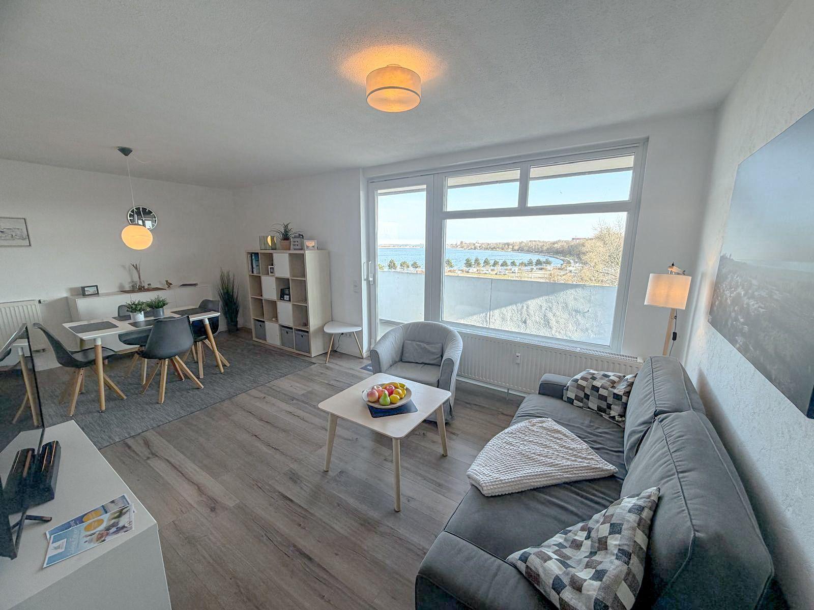 Wohnzimmer mit Blick auf Wasser, Sofa, Sessel und Esstisch.