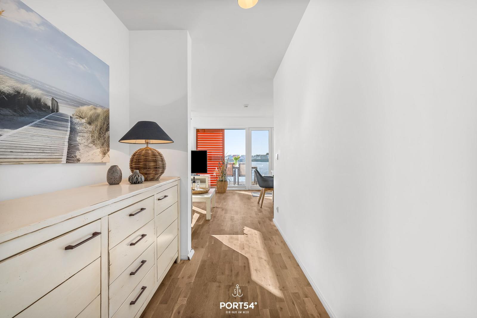 Flur mit Schrank, Wandbild und Blick in Wohnbereich mit Terrasse.