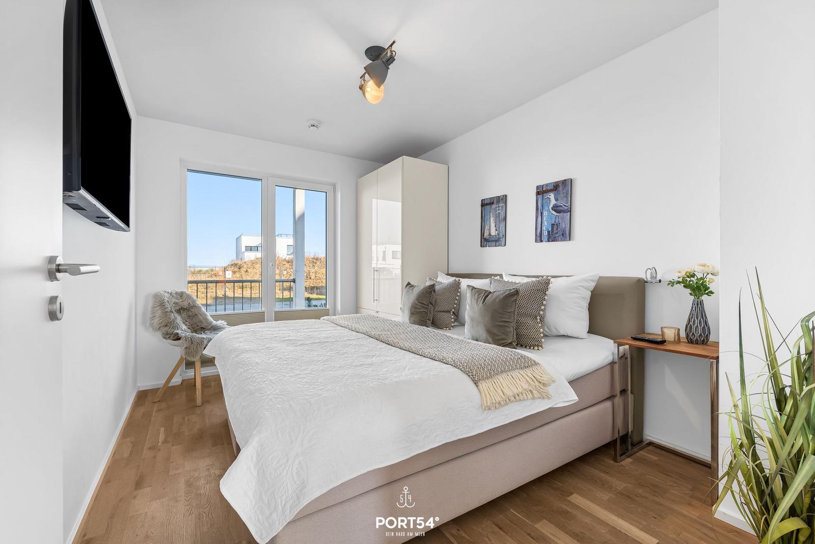Schlafzimmer mit Bett, TV und Balkonansicht