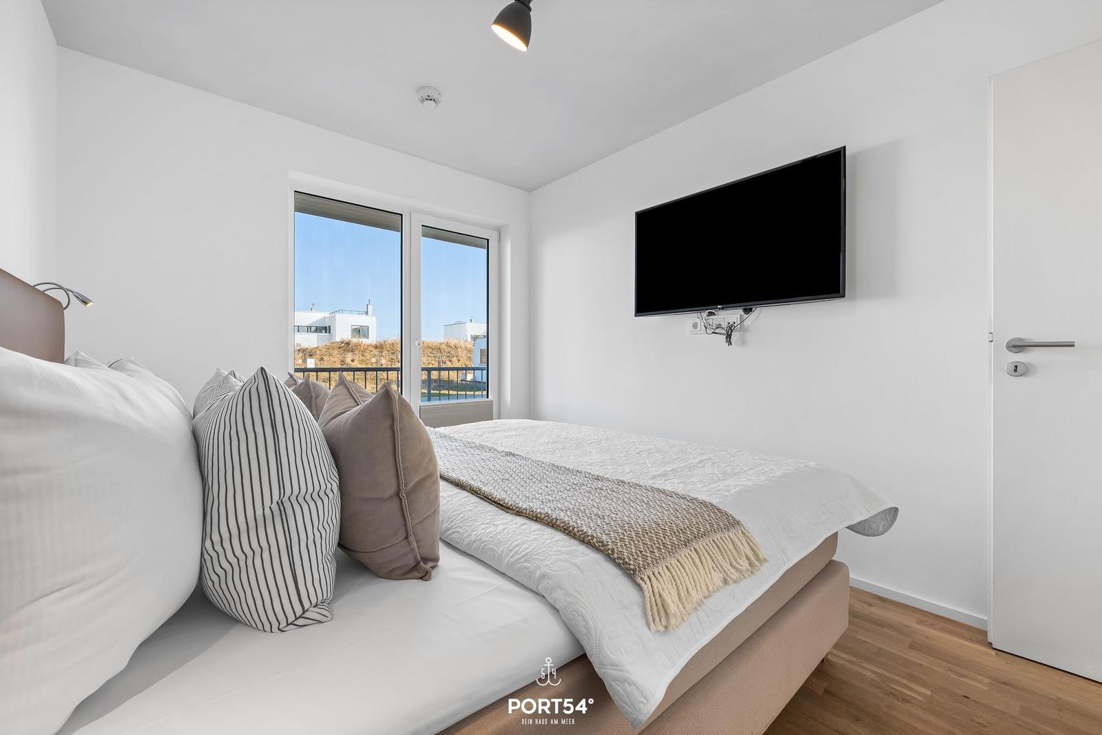 Schlafzimmer mit Bett, TV und Fenster zur Aussicht.
