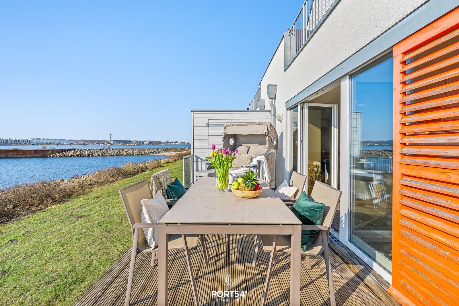 Terrasse mit Tisch, Stühlen und Blick auf Wasser