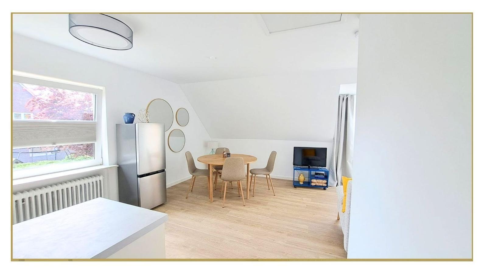 Wohnraum mit Essbereich, Kühlschrank, Fernseher und Fenster mit Blick.