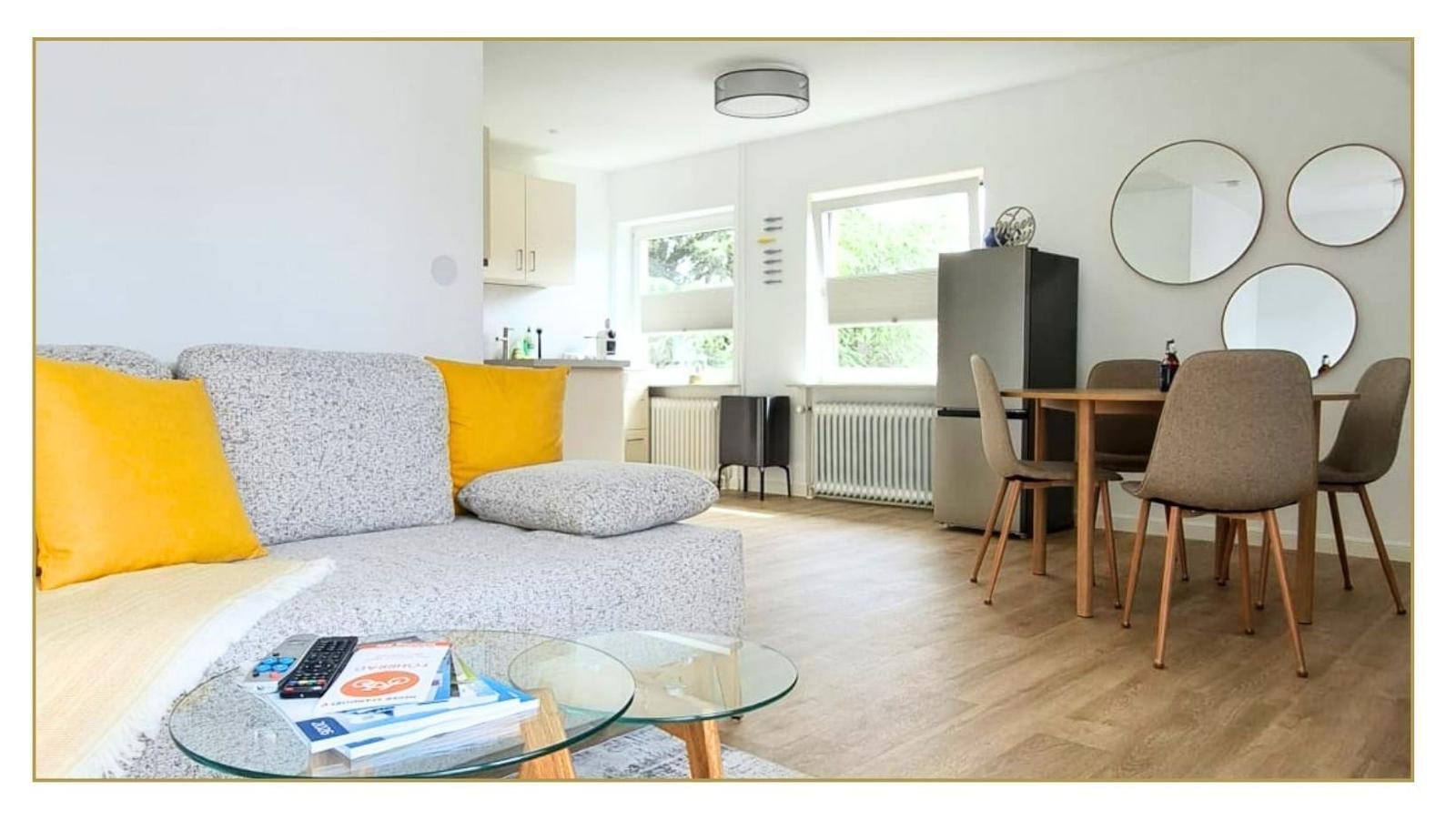 Wohn- und Essbereich mit Sofa, Esstisch und Küchenzeile.