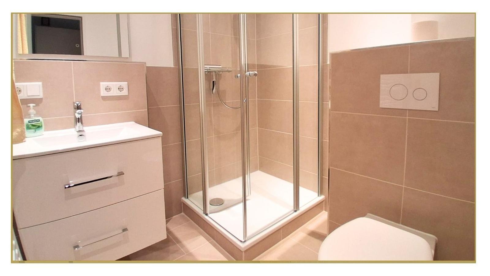 Badezimmer mit Dusche, Waschbecken und WC.