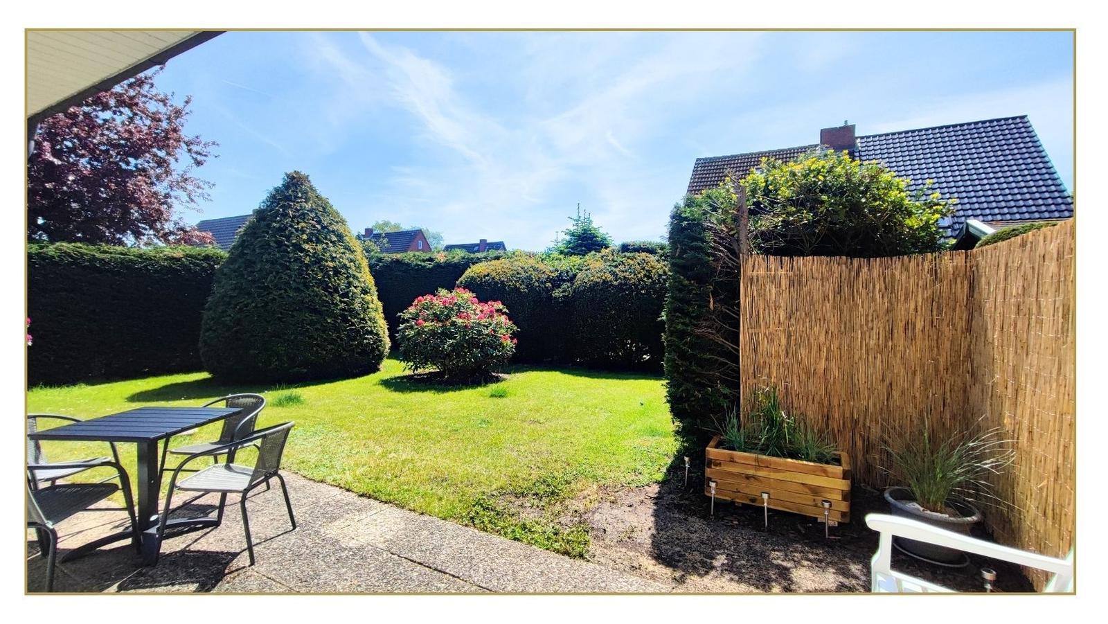 Hinterhof mit Garten, Tisch, Stühlen und Beete. Hintergrund: Wohnhaus und Hecken.
