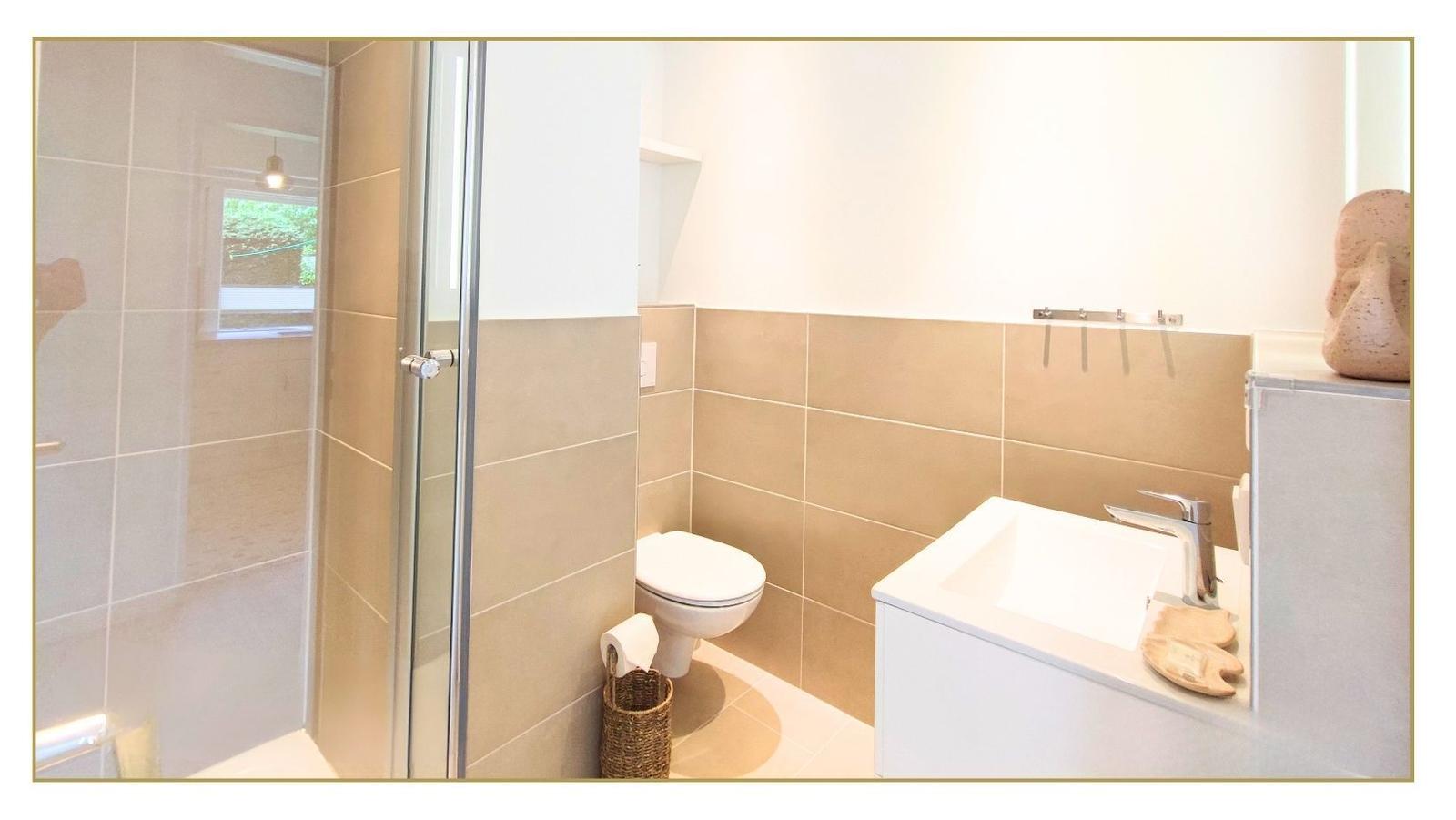 Badezimmer mit Dusche, Toilette und Waschbecken.